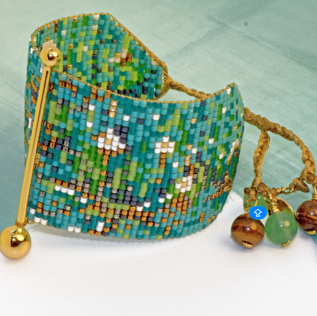 Decorative beaded bracelet with gold accents on a light green background
