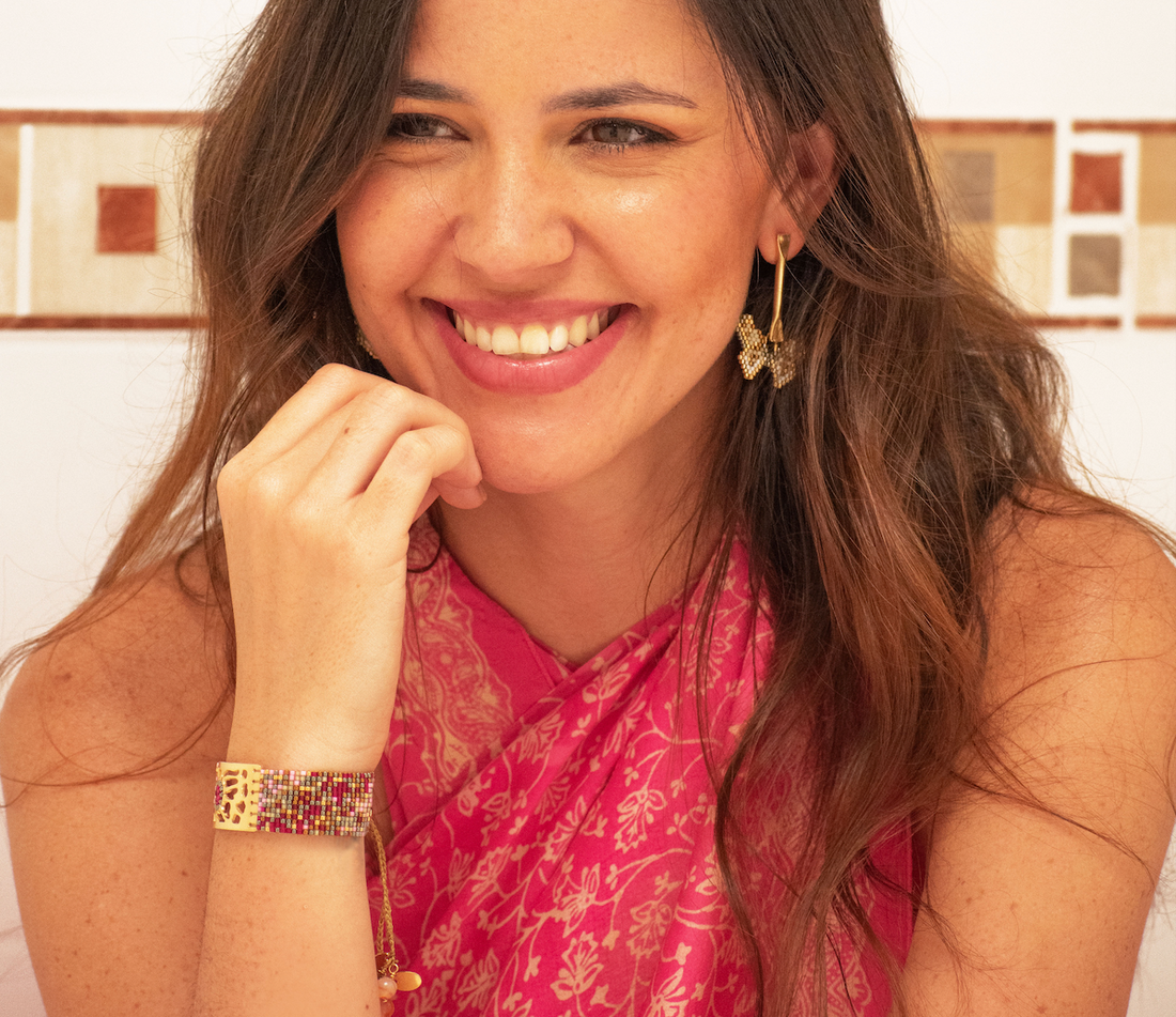 Mujer sonriente luciendo aretes y brazalete de joyería artesanal