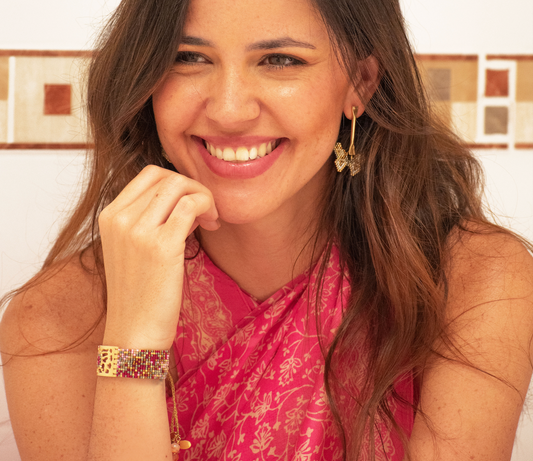 Mujer sonriente luciendo aretes y brazalete de joyería artesanal