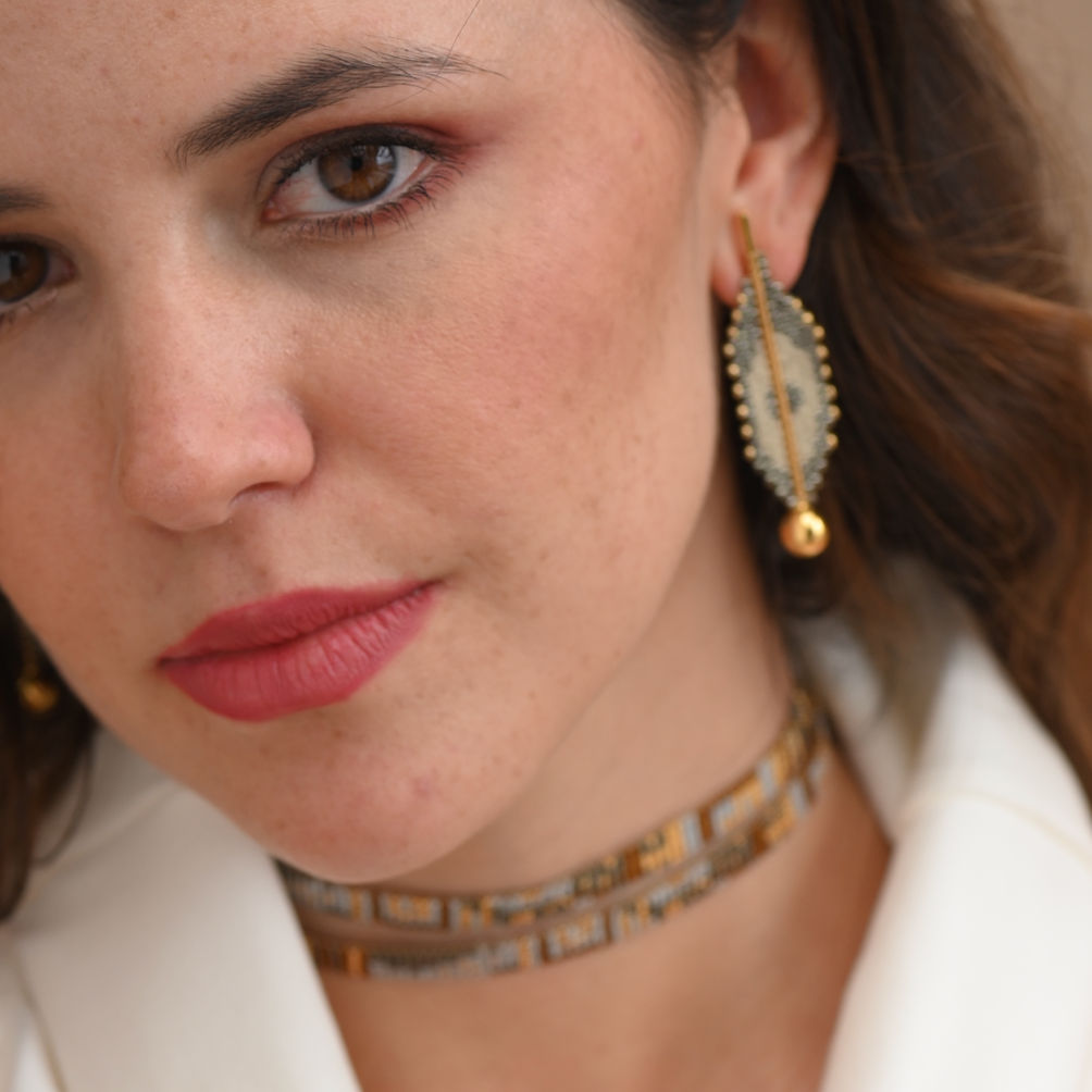 Close-up of a woman wearing gold earrings and a choker necklace.