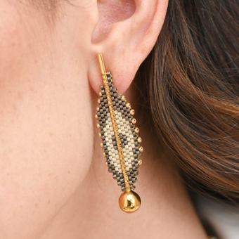 Gold leaf-shaped earring worn by a person