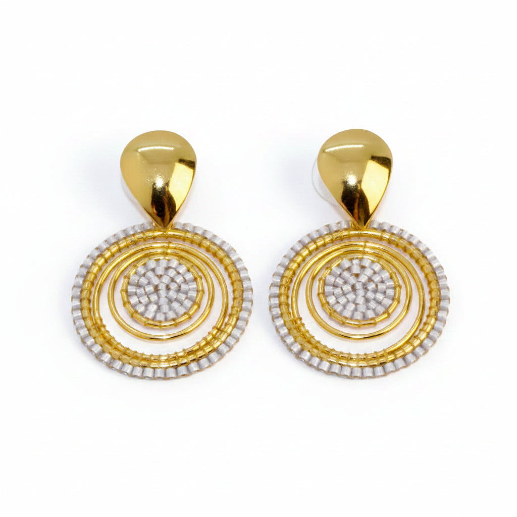 Gold and white circular earrings on a light gray background