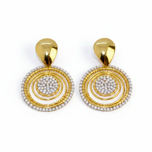 Gold and white circular earrings on a light gray background